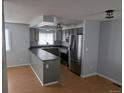 Open-concept kitchen featuring stainless steel appliances and sleek gray cabinets at 220 Mckinley Dr, Bennett, CO 80102