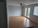 An empty living room featuring laminated floors, a ceiling fan, and access to a patio at 220 Mckinley Dr, Bennett, CO 80102