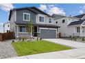 Attractive home with manicured lawn, gray tones, and a two-car garage at 45927 Wood Thrush Ave, Bennett, CO 80102