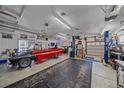 Spacious garage featuring an automobile lift, work space, and vintage red and black pick up truck at 34 Skyline Dr, Wheat Ridge, CO 80215