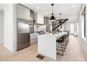 Modern kitchen boasts a quartz island with seating, stainless steel appliances, and sleek white cabinetry at 2230 W 36Th Ave, Denver, CO 80211