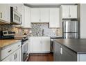 A modern kitchen features stainless steel appliances, white cabinets, and a mosaic tile backsplash at 1950 N Logan St # 1109, Denver, CO 80203