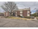 Brick apartment building featuring balconies, mature trees, and sidewalks in a quiet neighborhood at 5995 W Hampden Ave # 8C, Denver, CO 80227