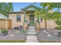 A charming brick home featuring a covered front porch with vibrant green trim and landscaping at 5704 Ammons St, Arvada, CO 80002