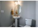 Stylish powder room with pedestal sink, oval mirror, modern lighting, and a tile floor at 2355 Saddle Back Ct, Fort Lupton, CO 80621