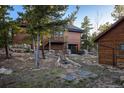 Back of home with a garage below and separate shop, surrounded by native vegetation and rock landscaping at 44 Linn Ln, Golden, CO 80403