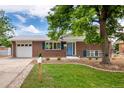 Inviting brick home featuring a well-kept lawn, charming blue door, and an attached one-car garage at 1011 Yeager Dr, Longmont, CO 80501