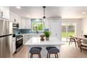 Modern kitchen featuring white cabinets, stainless steel appliances, an island with seating, and backyard views at 1011 Yeager Dr, Longmont, CO 80501