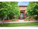 Inviting two-story home with lush landscaping, a front porch, and a vibrant blue front door at 8728 E 25Th Dr, Denver, CO 80238