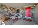 Inviting front porch with a red door, stone accents, comfortable seating, and a welcoming rug at 22227 E Hinsdale Ave, Aurora, CO 80016
