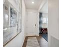 Bright hallway with hardwood floors, a white front door, and stylish decor, creating a welcoming entrance at 43124 Kawana Gulch St, Elizabeth, CO 80107