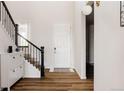 Bright entryway featuring wood floors, staircase with decorative iron railings, and modern light fixture at 5840 Longs Peak St, Brighton, CO 80601