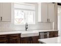 Well-lit kitchen featuring white subway tile backsplash, stainless steel appliances, and a farmhouse sink at 5840 Longs Peak St, Brighton, CO 80601