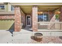 Charming front porch with brick columns, hanging planters, and a cozy entrance, inviting guests at 418 Hayloft Way, Brighton, CO 80601