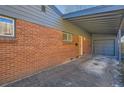 Side view of a brick home featuring a covered carport and a bright orange door at 345 S Forest St, Denver, CO 80246