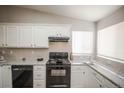 Modern kitchen with white cabinets, granite countertops, black appliances, and natural light from the window at 12555 Birch Ave, Thornton, CO 80241