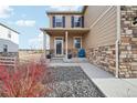 Charming front porch of a home with stone accents, colorful flowers and seating at 2042 Shadow Creek Dr, Castle Rock, CO 80104