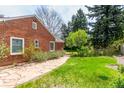 Landscaped backyard featuring a brick house, a stone walkway, and lots of greenery at 3756 S Forest Way, Denver, CO 80237