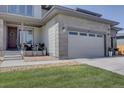 Close-up exterior showing a 2-car garage and the front porch with seating at 14445 Hop Clover Trl, Parker, CO 80134