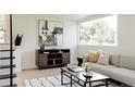 Bright living room features a modern sofa, black coffee table, media cabinet, and a large window at 1390 S Jasmine Way, Denver, CO 80224