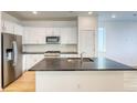 Bright kitchen with white cabinets, stainless steel appliances, island with a sink, and hardwood floors at 21242 E 63Rd Dr, Aurora, CO 80019