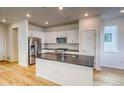 Bright kitchen with white cabinets, stainless steel appliances, island with sink, and hardwood floors at 21242 E 63Rd Dr, Aurora, CO 80019