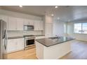 Modern kitchen featuring stainless steel appliances, gray countertops, white cabinets, and a center island with a sink at 21242 E 63Rd Dr, Aurora, CO 80019