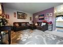 Cozy living room featuring comfortable leather furniture, a patterned rug, and a purple accent wall at 19258 E Kansas Dr, Aurora, CO 80017