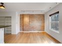 Bright living room features exposed brick wall, wood floors, track lighting, and a window at 2306 Glenarm Pl # 206, Denver, CO 80205