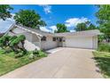 Single-story home featuring a long driveway leading to an attached garage, complemented by lush front yard landscaping at 3695 W Monmouth Ave, Littleton, CO 80123