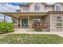 Inviting covered front porch with brick details and a well-maintained lawn with green door at 5483 Gunnison Dr, Frederick, CO 80504