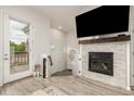 Bright living room with a modern fireplace, wood floors, and access to outdoor patio at 619 Brennan Cir, Erie, CO 80516
