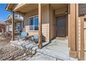 Cozy front porch features comfortable seating, a wood support structure and a brown front door at 1820 Taos St, Brighton, CO 80603