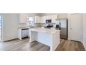 Bright kitchen featuring stainless appliances, white cabinets, a kitchen island, and wood-look flooring at 15285 Milwaukee St, Thornton, CO 80602