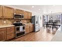 Well-lit kitchen features stainless steel appliances, warm wood cabinets, and a cozy breakfast nook at 1128 S Duquesne Cir, Aurora, CO 80018