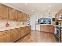 Spacious kitchen featuring ample wood cabinetry, tiled backsplash, stainless steel appliances, and wood floors at 1128 S Duquesne Cir, Aurora, CO 80018