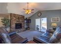 Cozy living room with stone fireplace, ceiling fan, and sliding glass doors at 1128 S Duquesne Cir, Aurora, CO 80018