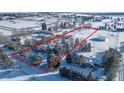 Aerial view of a property covered in snow, bordered in red, nestled among trees and other homes at 8530 W Jefferson Ave, Denver, CO 80235