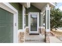 Close-up of front entrance with stone accents, green siding, and a well-lit porch at 19634 E Clear Creek Trl, Parker, CO 80134