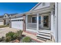 Inviting front porch of this home with white pillars, brick accents, and a well-manicured landscape at 15685 E 50Th Ave, Denver, CO 80239
