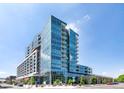 Modern condo with glass facade, outdoor balconies, and street-level landscaping under a bright sky at 4200 W 17Th Ave # 411, Denver, CO 80204