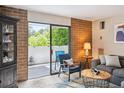 Relaxing living room with a blue chair, brick accent wall, and sliding doors opening to the outside at 2880 S Locust St # 305N, Denver, CO 80222