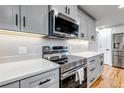 Updated kitchen showcasing a stainless steel microwave, oven, gas range, and gray cabinets at 10025 W 8Th Ave, Lakewood, CO 80215