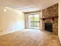 Living room with a stone fireplace, carpet flooring, and sliding glass doors to a balcony at 1870 S Pitkin Cir # B, Aurora, CO 80017
