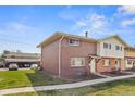 Exterior view of the two-story brick home with adjacent parking area and well-kept lawn at 9044 E Nassau Ave, Denver, CO 80237