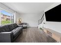 Bright living room with hardwood floors, a large window, and a modern television setup above a stylish cabinet at 9044 E Nassau Ave, Denver, CO 80237