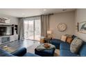 Cozy living room with a blue sectional, dark wood floors, and sliding glass doors at 1868 Makley Loop, Castle Rock, CO 80104