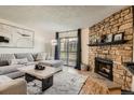 Cozy living room with a stone fireplace, plush seating, and sliding glass doors to a patio at 8225 Fairmount Dr # 104, Denver, CO 80247
