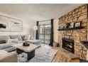 Bright living room with stone fireplace, sliding glass doors to the outside, and contemporary decor at 8225 Fairmount Dr # 104, Denver, CO 80247