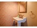 Stylish powder room showcasing vintage-inspired wallpaper and a classic pedestal sink with elegant fixtures at 131 Fox St, Denver, CO 80223
